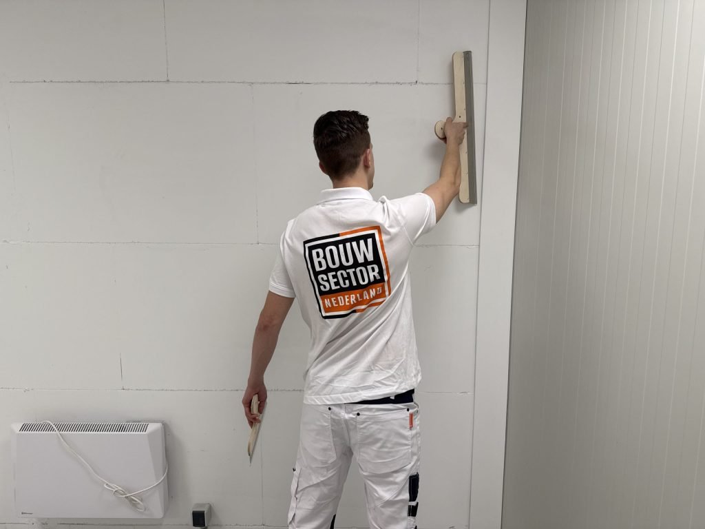 Stukadoor van Bouwsector Nederland trekt met een brede spaan een wand vlak